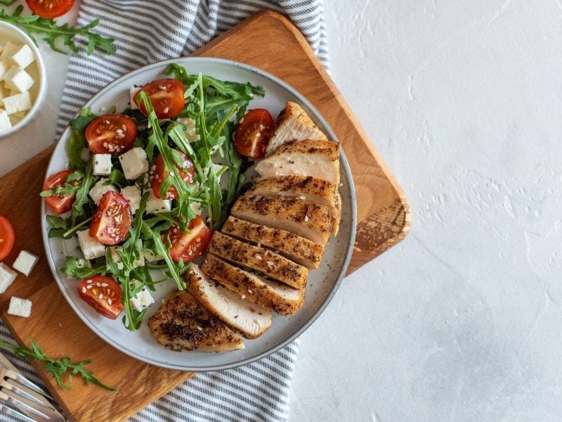 Holzbrett und Teller mit Sommer-Salat mit Pute