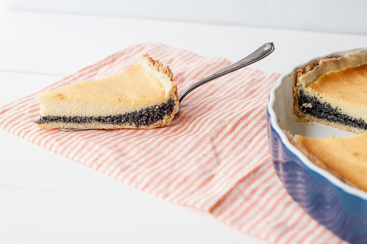 Käsekuchen mit Mohnfüllung, Stpck auf pinkem Tuch, daneben Tarteform