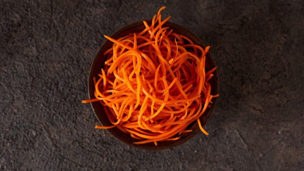 Pikanter Karottensalat mit einer Marinade aus orientalischen Gewürzen und Chili, serviert in einer dunklen Schale auf einem steinernen Untergrund.