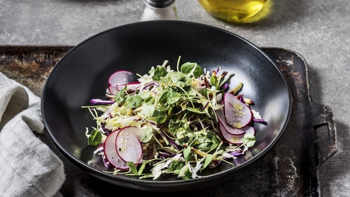 Knackiger Rohkostsalat, bestehend aus Rotkraut, Spitzkohl, Spinat und Radieschen, getoppt mit feiner Vinaigrette und Sesam