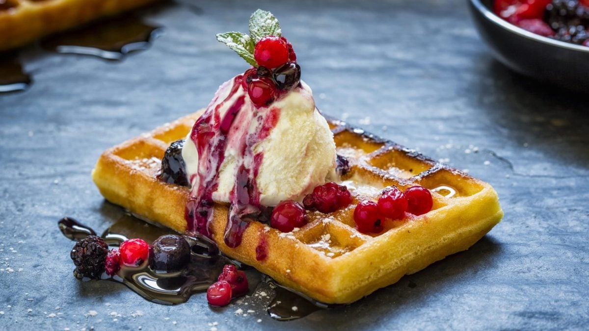 Saftige Waffeln mit Honig-Eis vor blauem Hintergrund