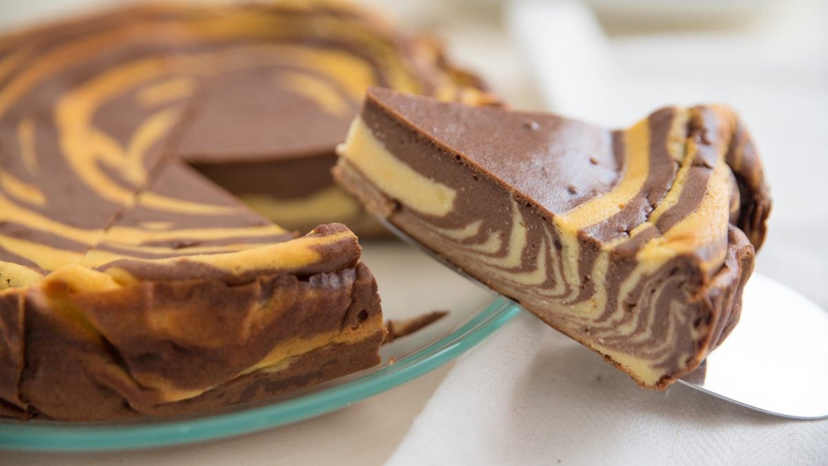 Runder Zebra-Käsekuchen mit Vanille und Schokoladenstreifen auf einer Glasplatte