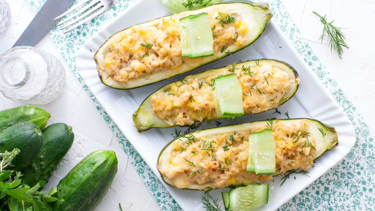 Gefüllte Zucchini mit Hähnchen-Risotto auf weißem Teller, daneben Zucchini