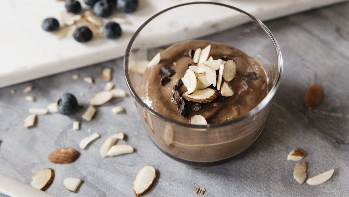 Schokoladiger Chia Pudding mit Mandeln in kleinem Glas, daneben Mandelsplitter