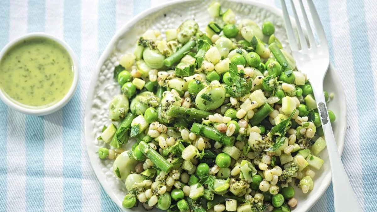 Grüner Salat mit Estragon-Dressing auf weißem Porzellan vor hellblau-weiß gestreiftem Hintergrund