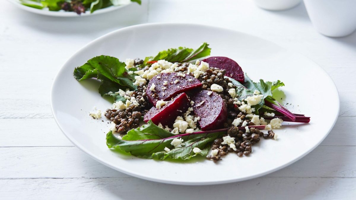 Linsensalat mit Rote Bete und Feta auf weißem teller auf einer weißen Holztischplatte