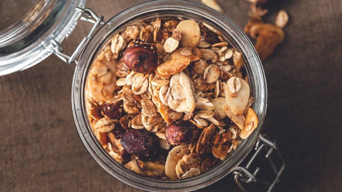 Geröstetes Müsli mit Haferflocken, Nüssen und Trockenfrüchten, serviert in einem Einweckglas auf einem Holztisch.