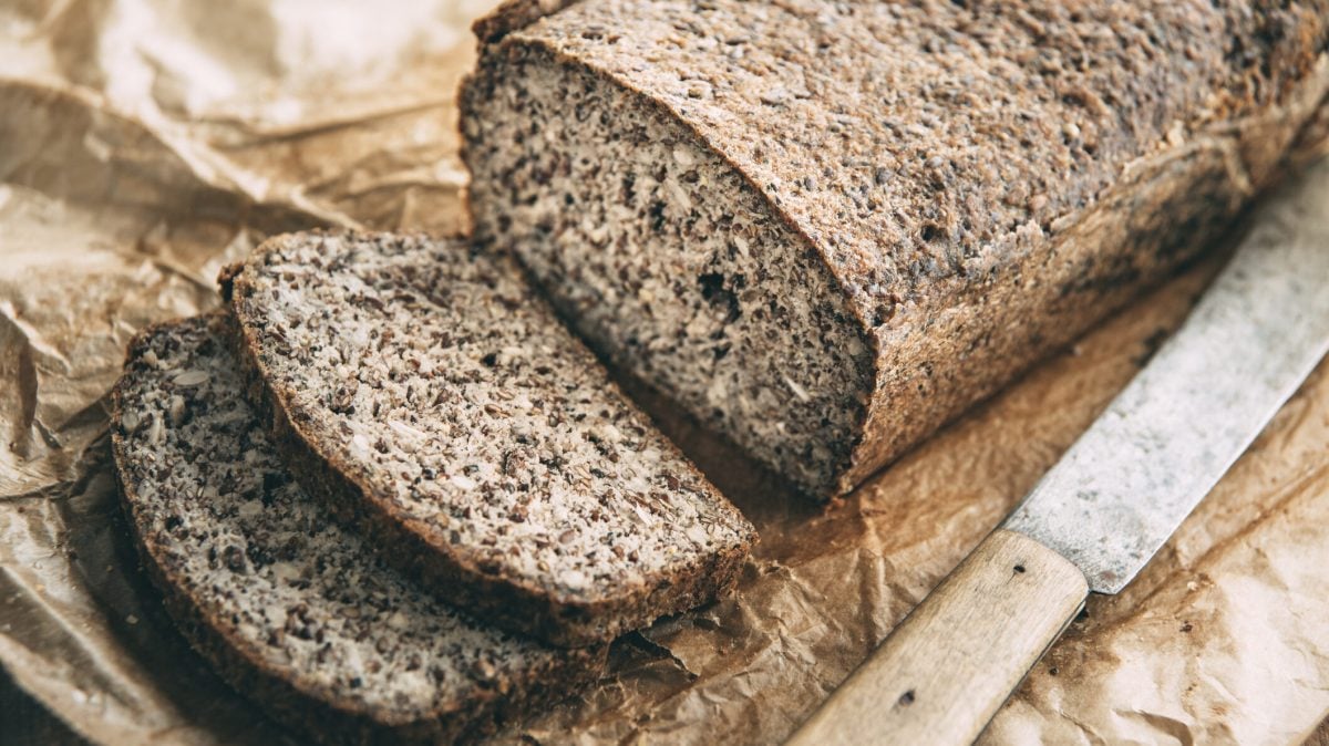 Glutenfreies Chia-Brot mit Quark, daneben Messer auf Holzbrett