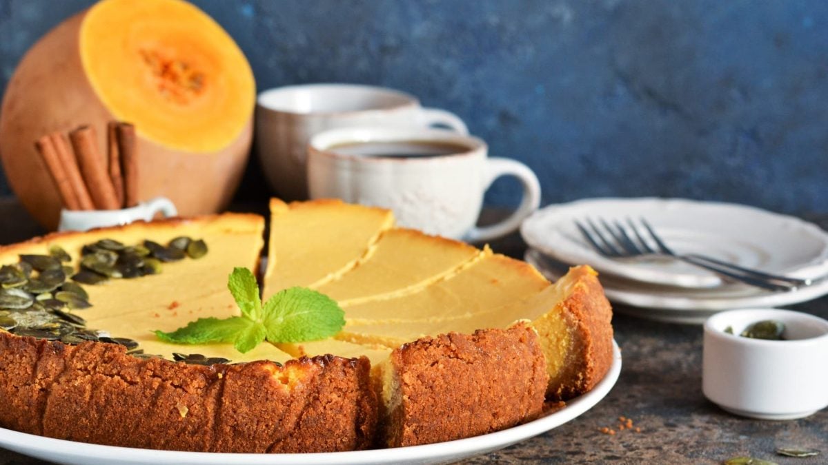 Cremiger Kürbis-Cheesecake auf weißem Teller garniert mit Kürbiskernen