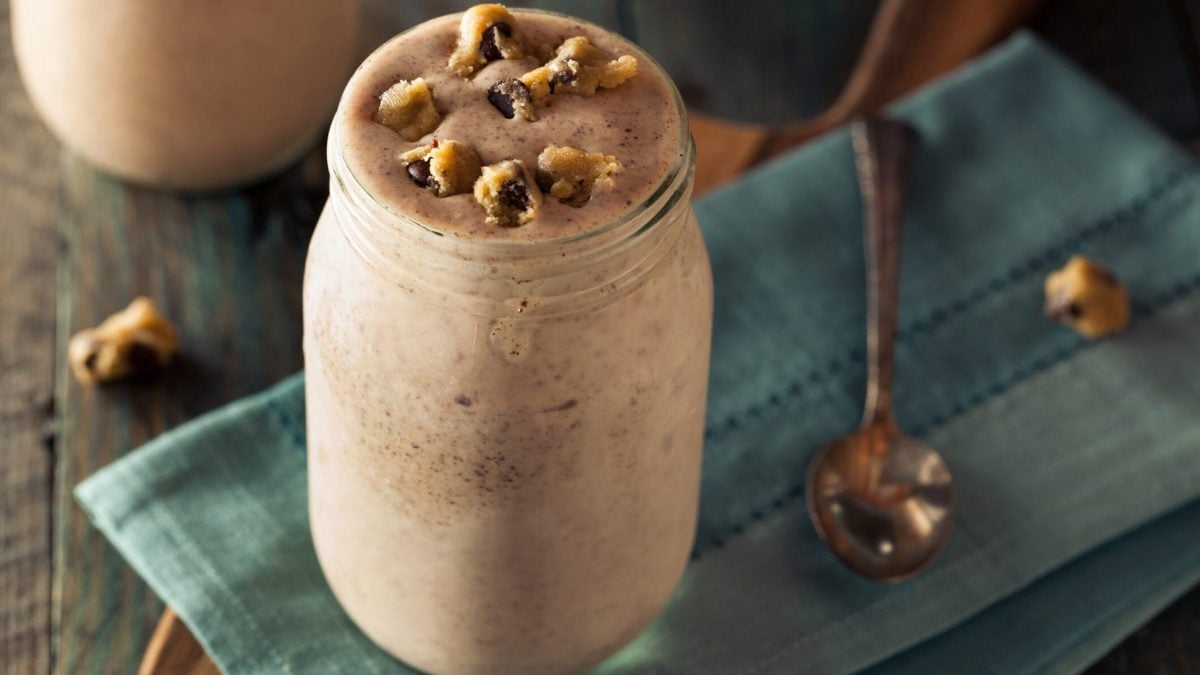 Veganer Cashew-Shake mit Schokolade in großem Glas, garniert mit Keksstücken