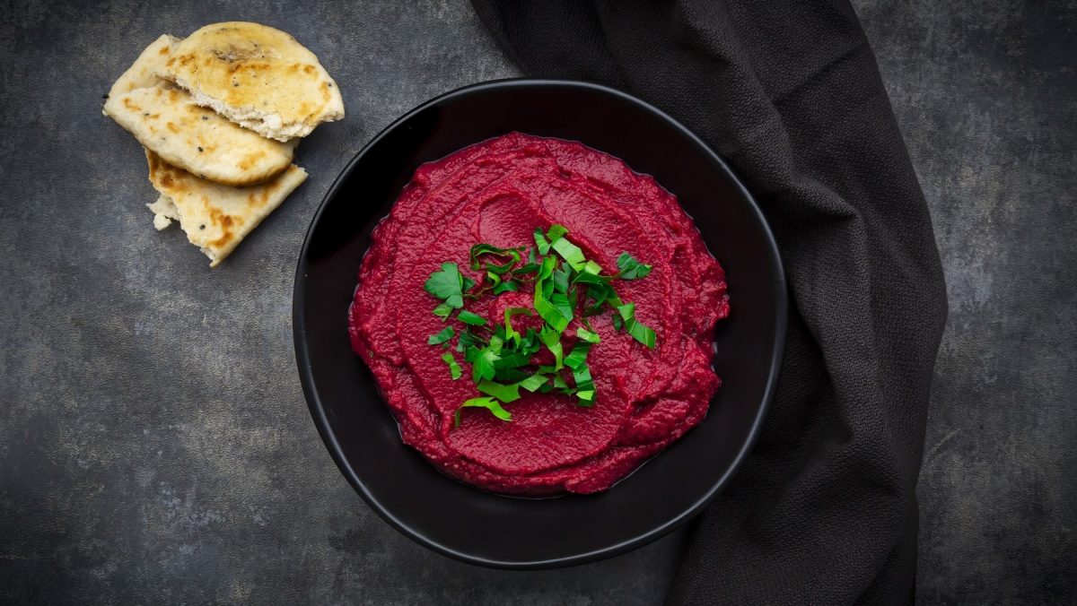 Cremiger Rote Bete-Aufstrich in einer scharzen Schale, garniert mit frischer Petersilie und angereicht mit Stücken von Fladenbrot