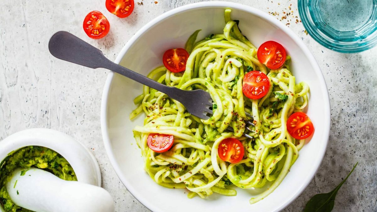 Zucchini-Nudeln mit selbst gemachtem Pesto in weißer Schüssel, daneben Pesto