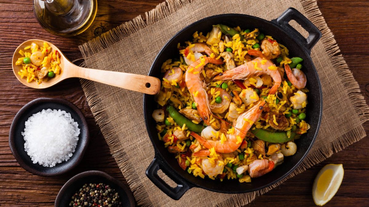 Paella mit Meeresfrüchten und Hähnchen in Pfanne auf Tuch