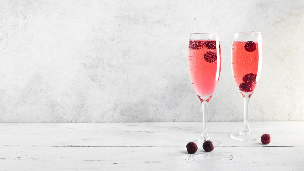 Fruchtiger Kir Royal in zwei Sektgläsern mit Beeren garniert