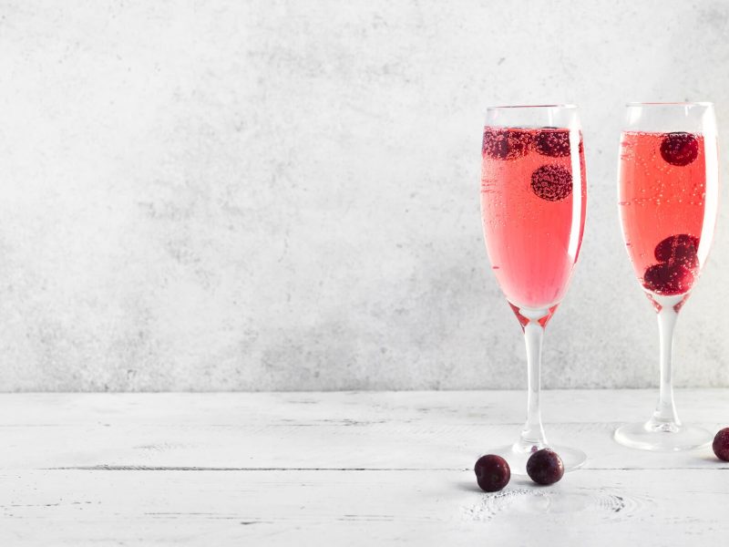 Fruchtiger Kir Royal in zwei Sektgläsern mit Beeren garniert