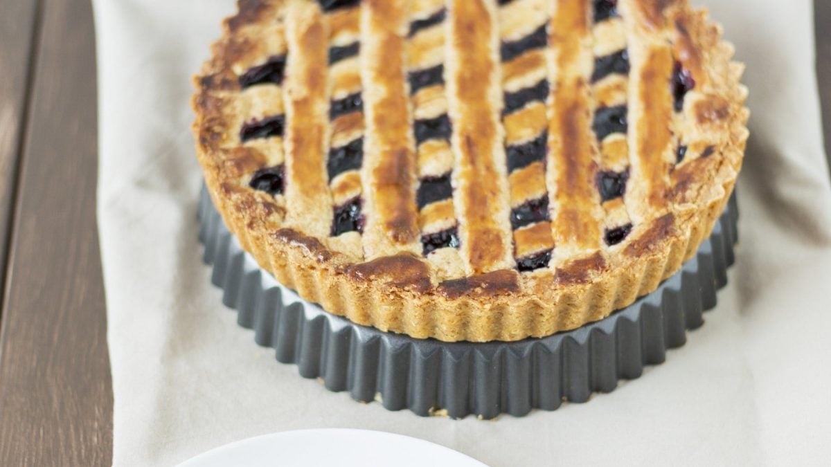 Saftige und nussige Linzertorte mit Johannisbeerfüllung und schönem Gittermuster auf hellem Untergrund.
