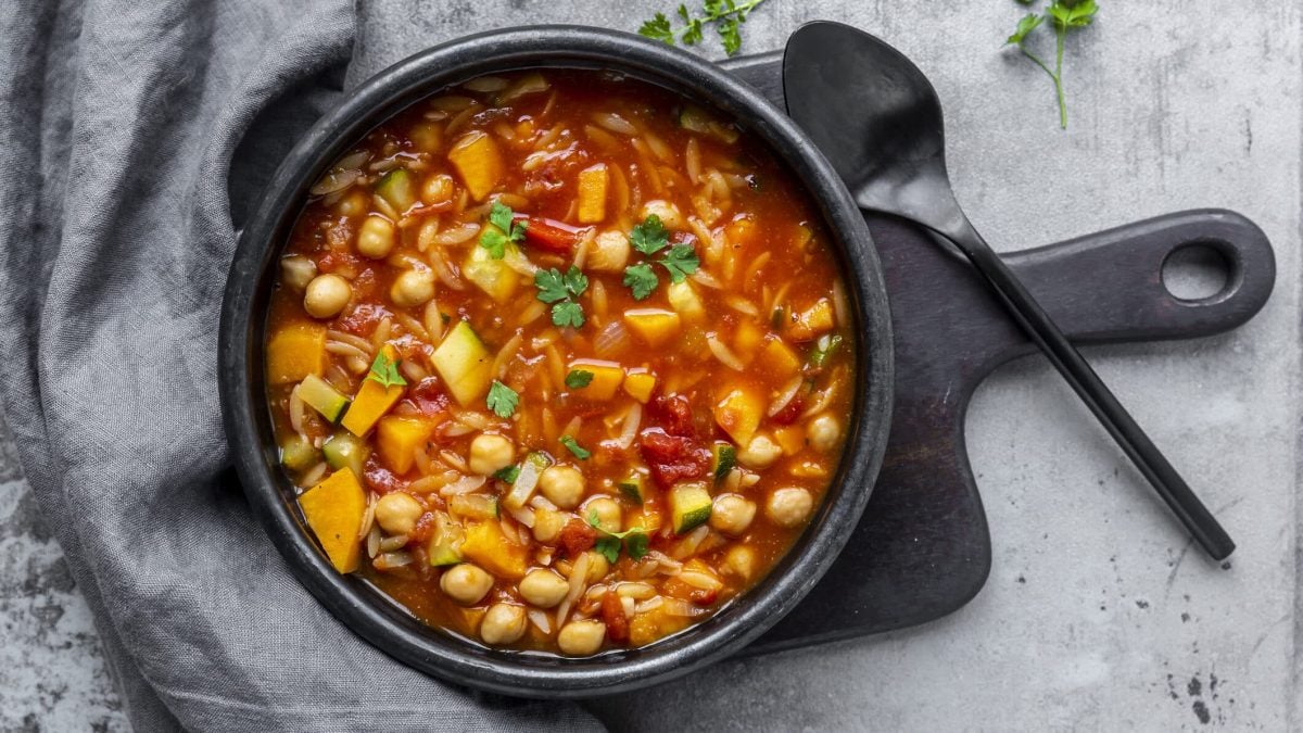 Leichter Kichererbsen-Eintopf mit Zucchini in Pfanne auf schwarzem Brett