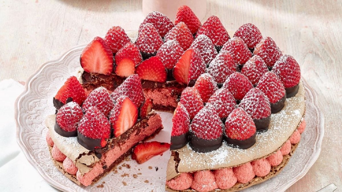 Auf einem Tisch steht eine Erdbeer-Macaron-Torte