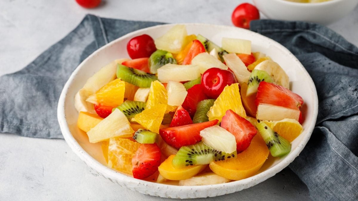 Einfacher Obstsalat mit Vanille in Schüssel, daneben graues Küchenhandtuch