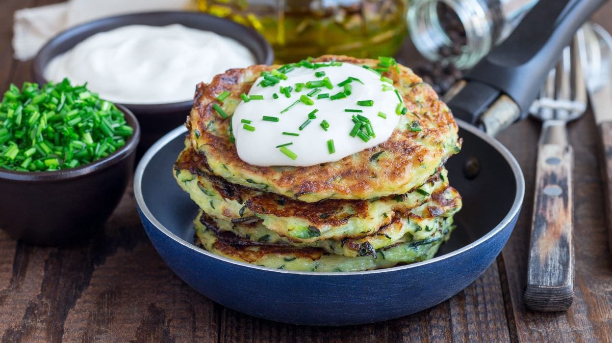 Zucchini-Karotten-Puffer mit selbst gemachtem Quark-Dip in Teller, dahinter Schüssel mit Dip