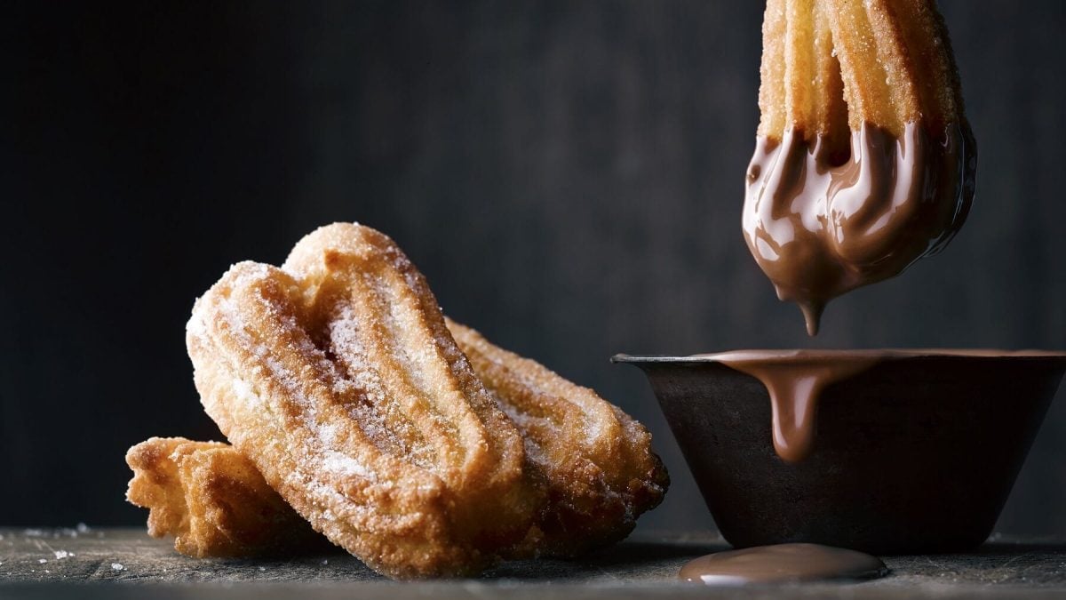 Churros mit Schokoladensauce vor dunklem Hintergrund