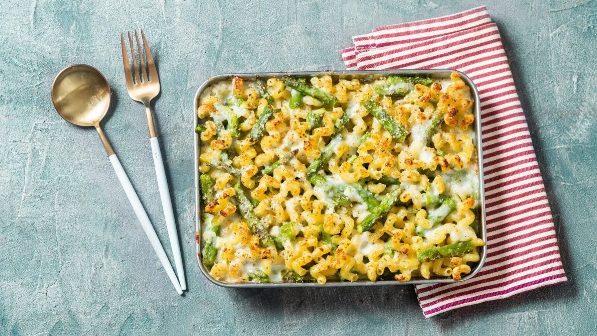 Grüner Spargel-Auflauf mit Hörnchennudeln neben einer rot-weiß gestreiften Serviette und Besteck