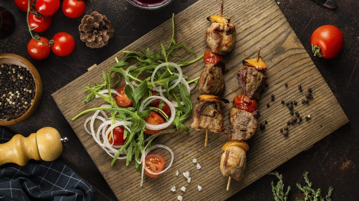 Holzbrett mit würzigen Steak-Spieße mit Rucola-Salat