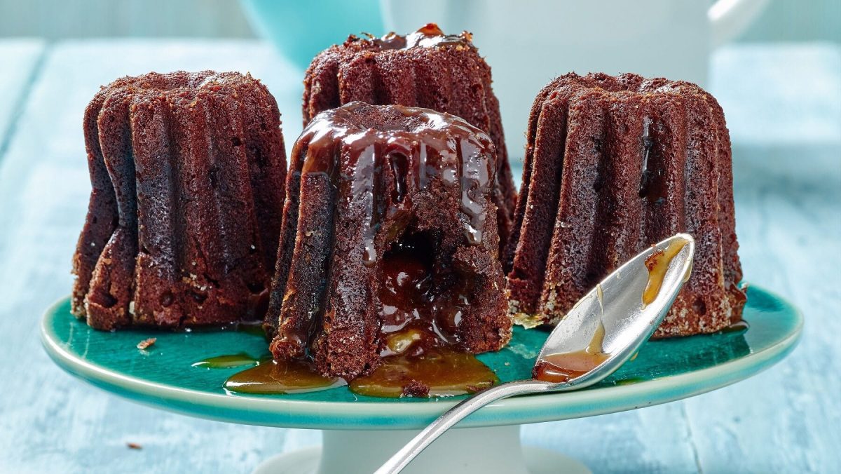 Canelés mit flüssigem Karamellkern auf blauer Kuchenplatte