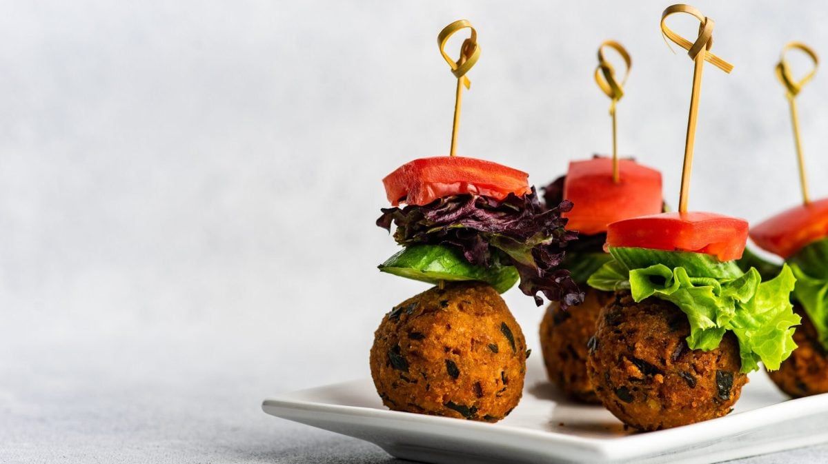 Spieße mit Kürbis-Falafel auf weißem Teller vor hellem Hintergrund