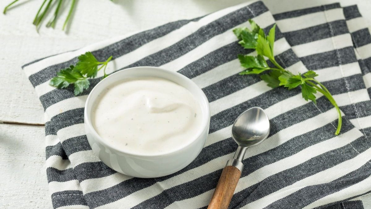 Ranch-Dressing auf gestreiftem Tuch mit Petersilie und einem Löffel