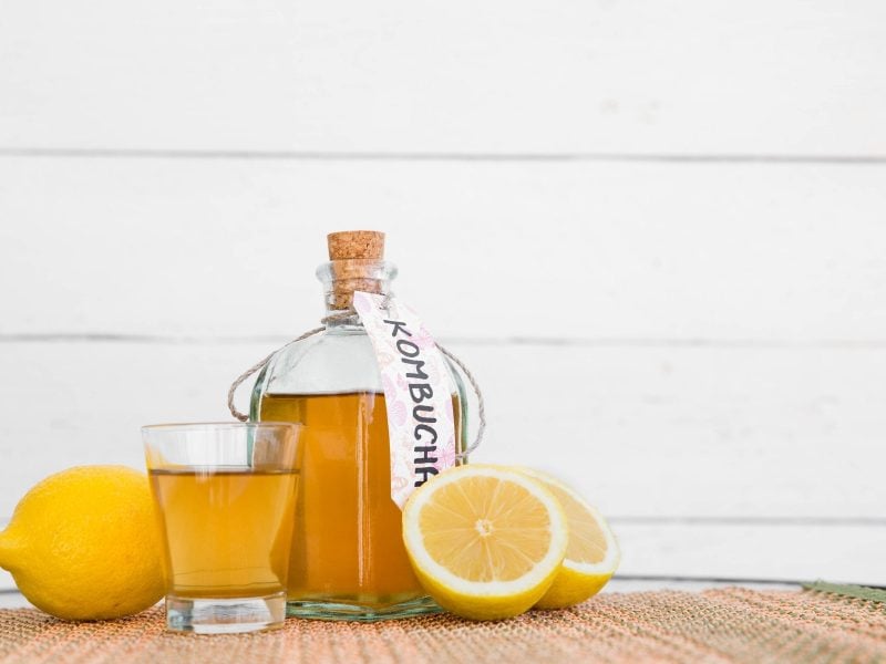 Dürfen Schwangere Kombucha trinken? Flasche und Glas mit Kombucha und Zitronen