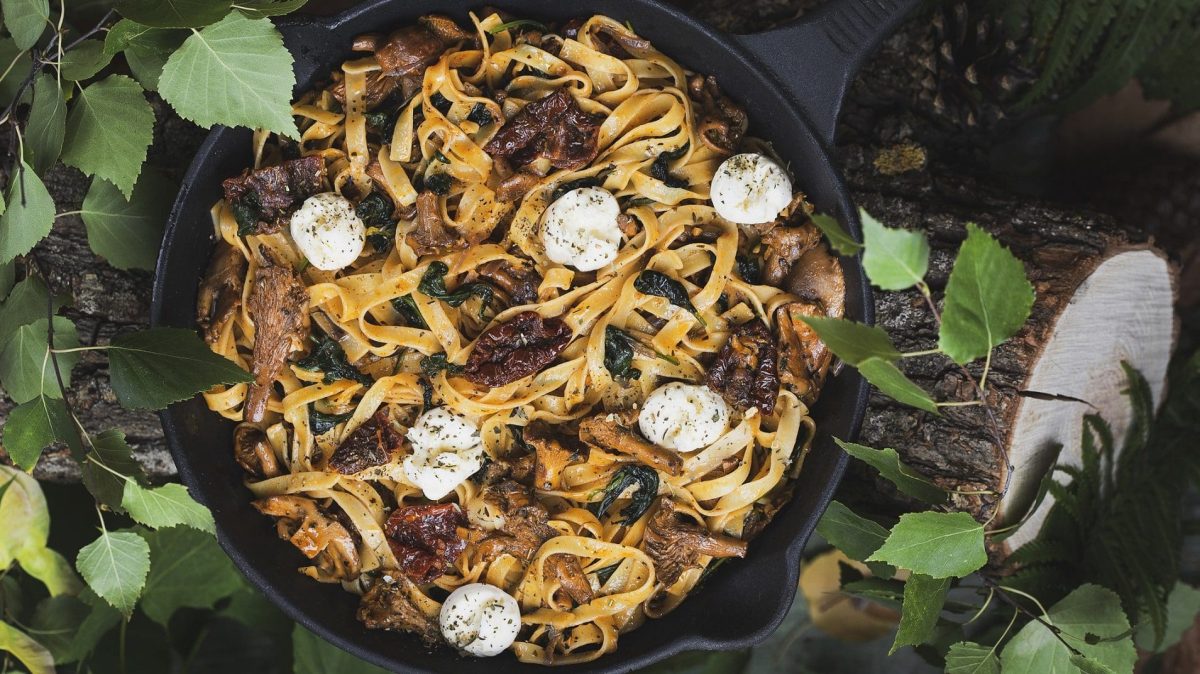 Bandnudeln mit Pfifferlingen und Frischkäsesoße, belegt mit Mozzarella in einer Pfanne.