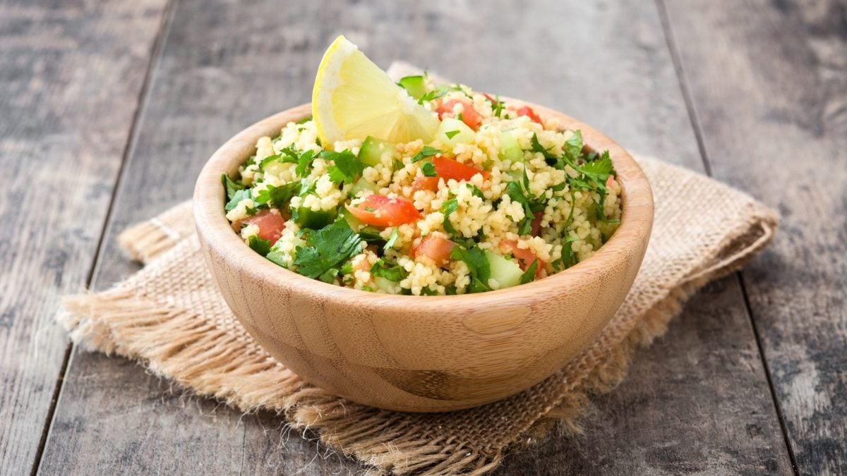 Bulgur-Tomatensalat mit Petersilie in einer Holzsschale auf einem Holztisch
