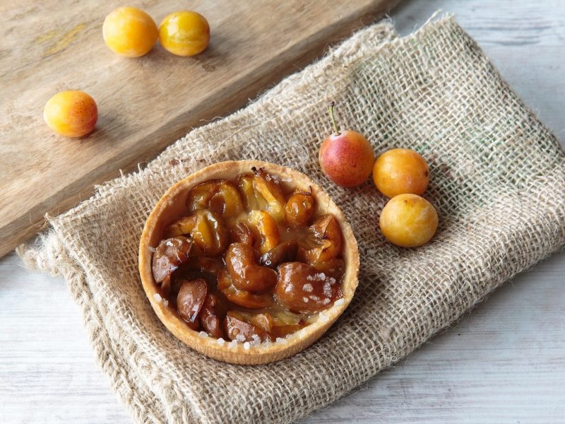 Mirabellenkuchen und Mirabellen mit Holzbrett und Leinentuch