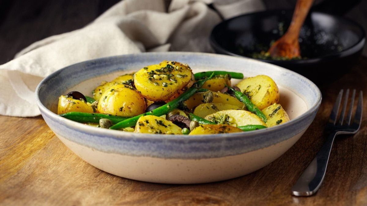 Schüssel mit Kartoffel-Spargelsalat, daneben grüner Spargel und Radieschen