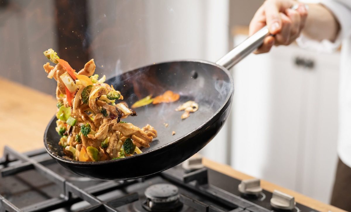 Thai-Pfanne mit Rindfleisch wird über Herd geschwenkt