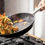 Thai-Pfanne mit Rindfleisch wird über Herd geschwenkt