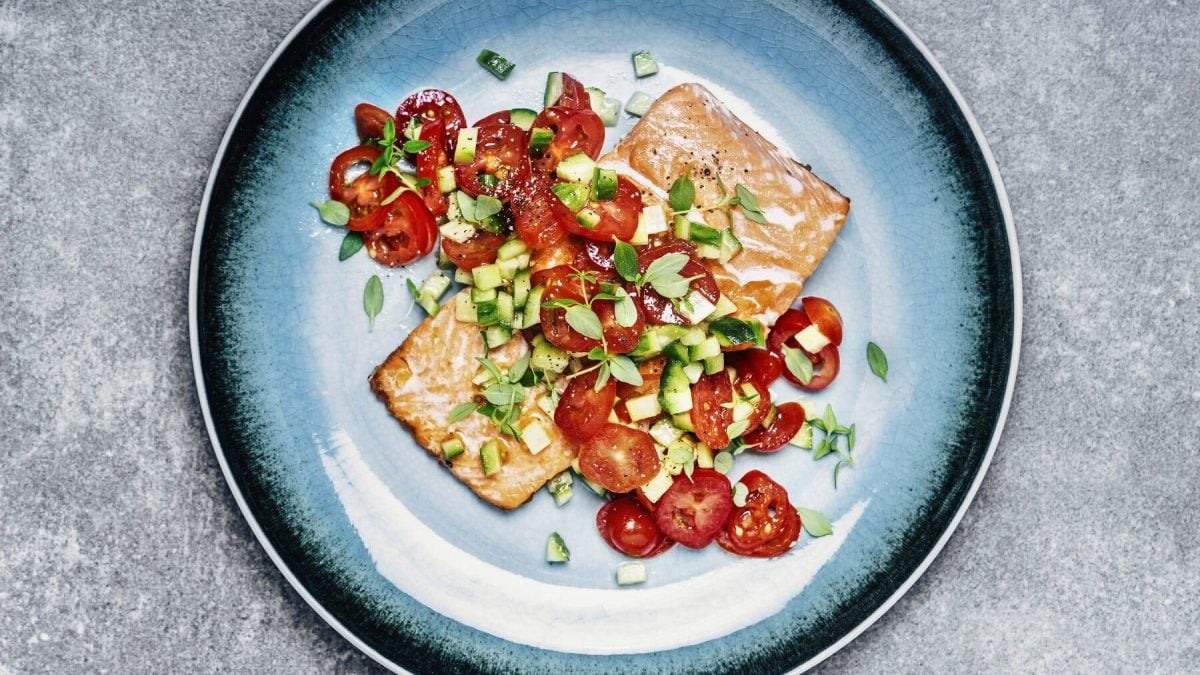 Lachs mit Gurken-Tomaten-Salat auf blauem Teller