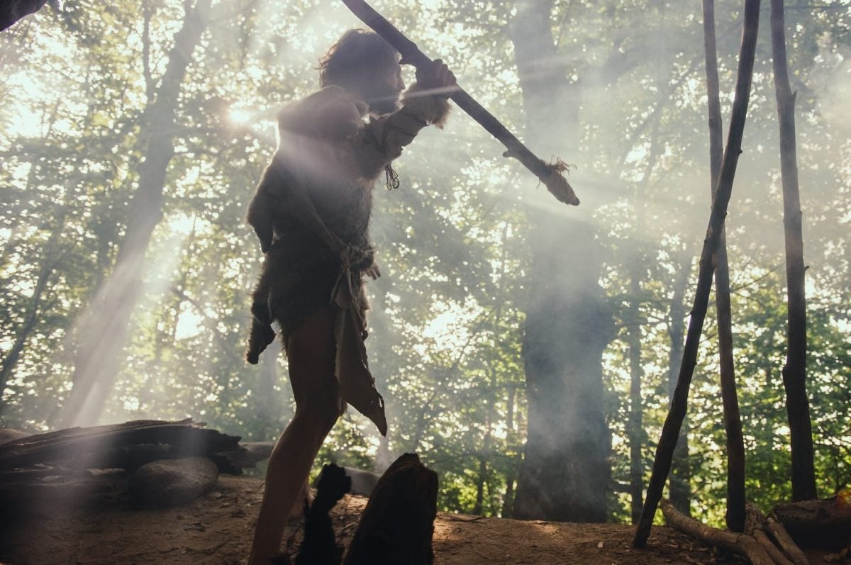 Steinzeitmensch läuft durch den Wald und sammelt Essen für die Paleo-Diät