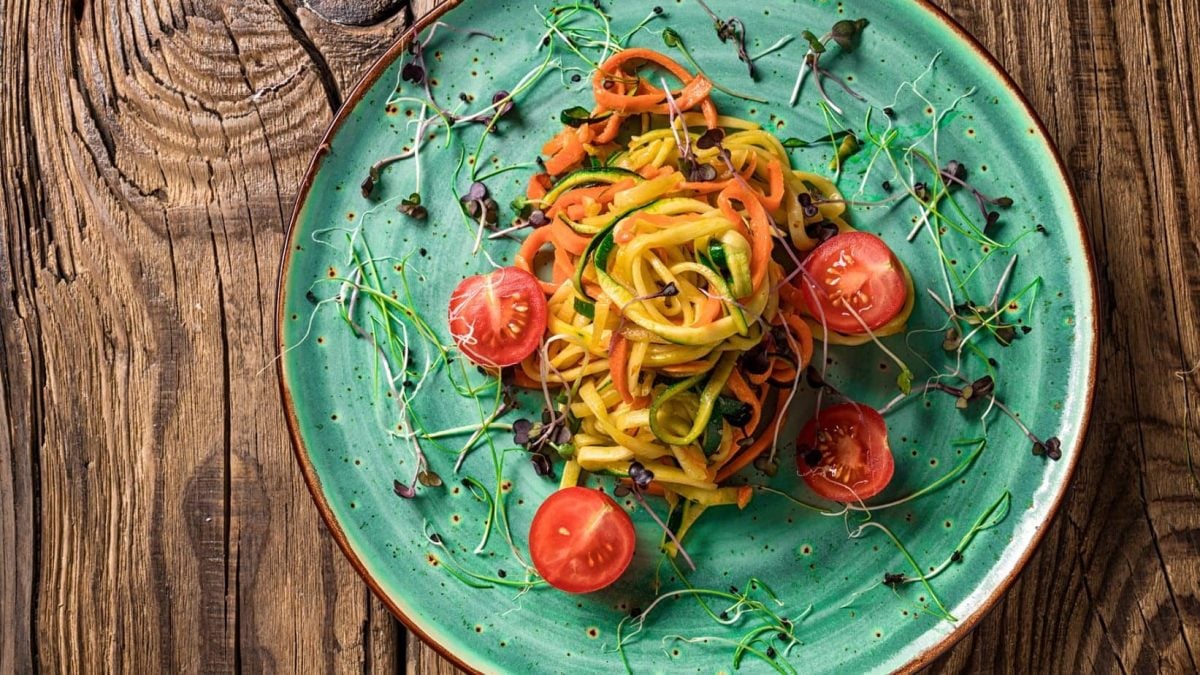 Spaghetti mit Zucchini und Möhren, dekoriert mit Kresse und Tomatenhälften.