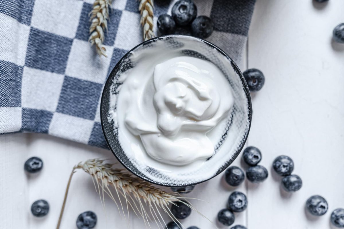 Warum rahmt sahne auf: eine Schale mit Schlagsahne, drumherum liegen Blaubeeren, Getreide und ein Geschirrtuch
