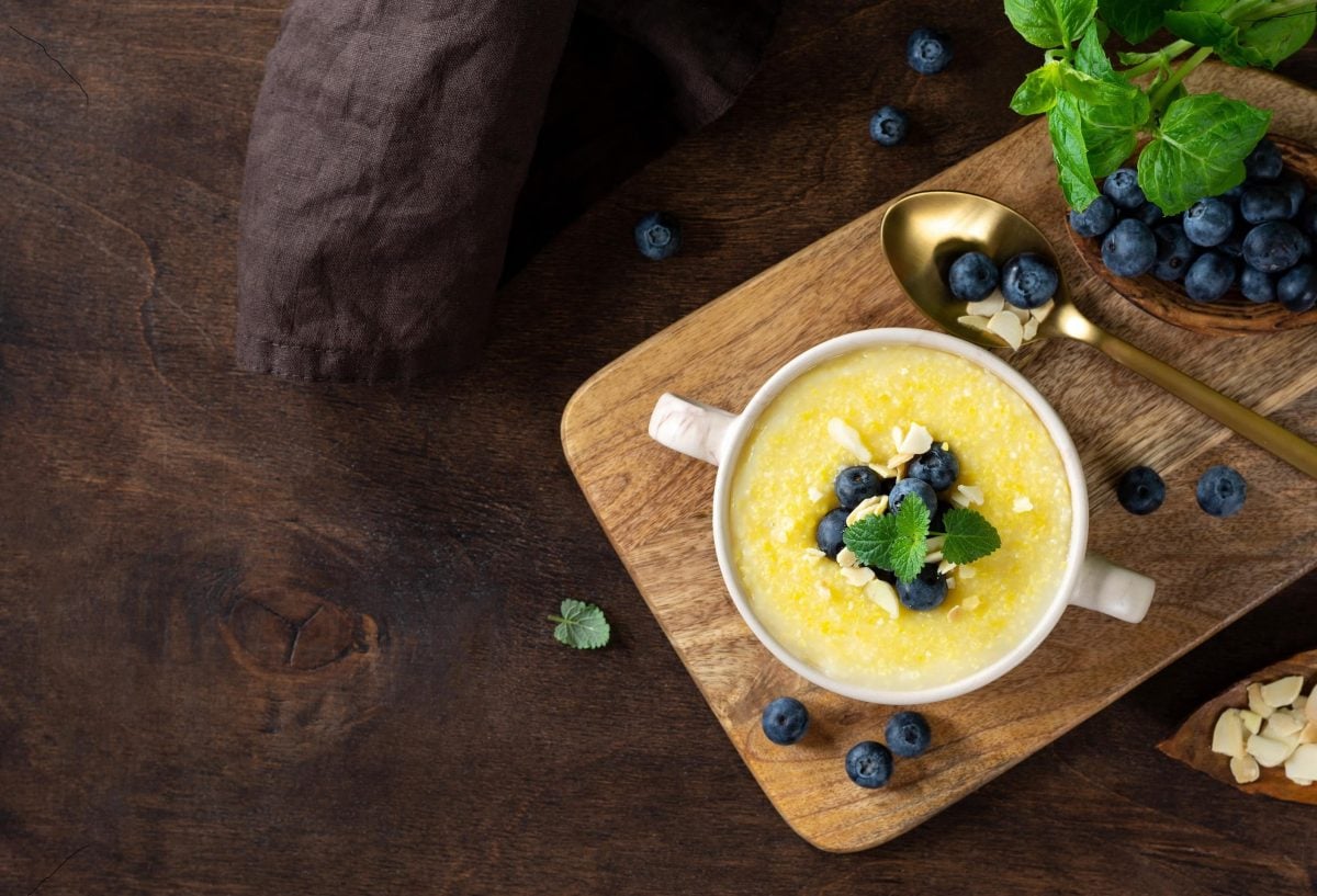 Cremige Polenta ist in einer Schüssel angerichtet mit Blaubeeren als Topping.
