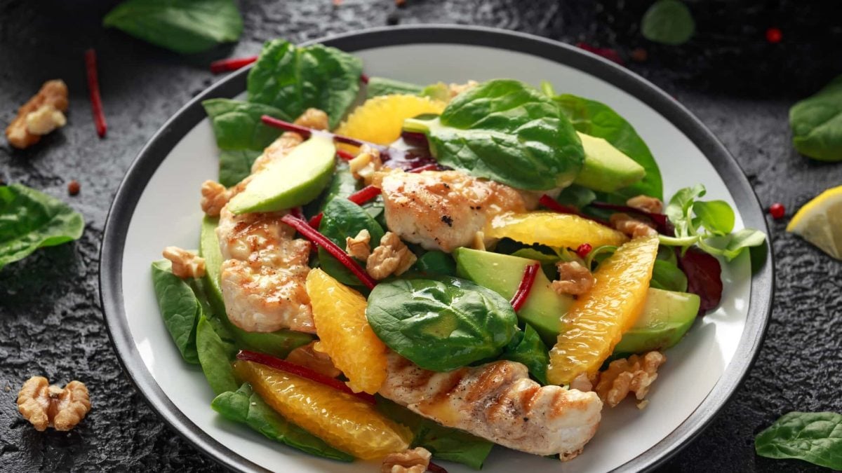 Mangold-Salat mit Hähnchen und Orangen, dazu noch Avocado und Walnüsse. Alles auf einem Teller.