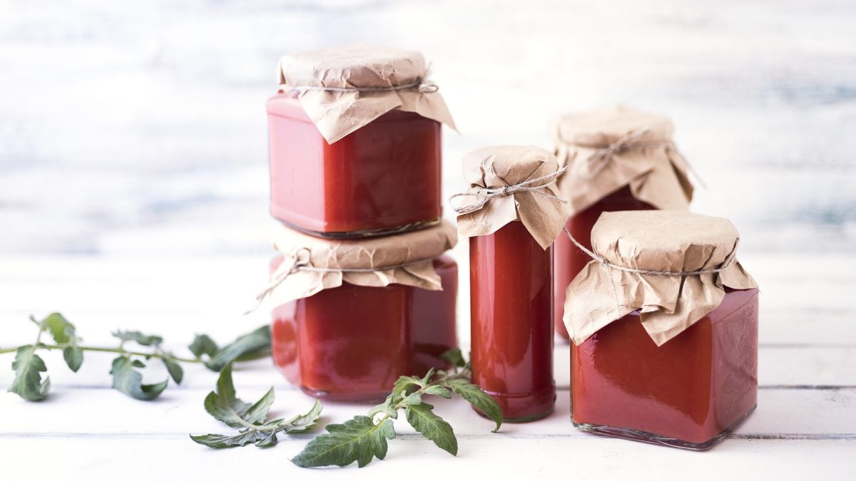 Einige Gläser mit selbst gemachtem Ketchup, die vor einem hellen Hintergrund stehen.