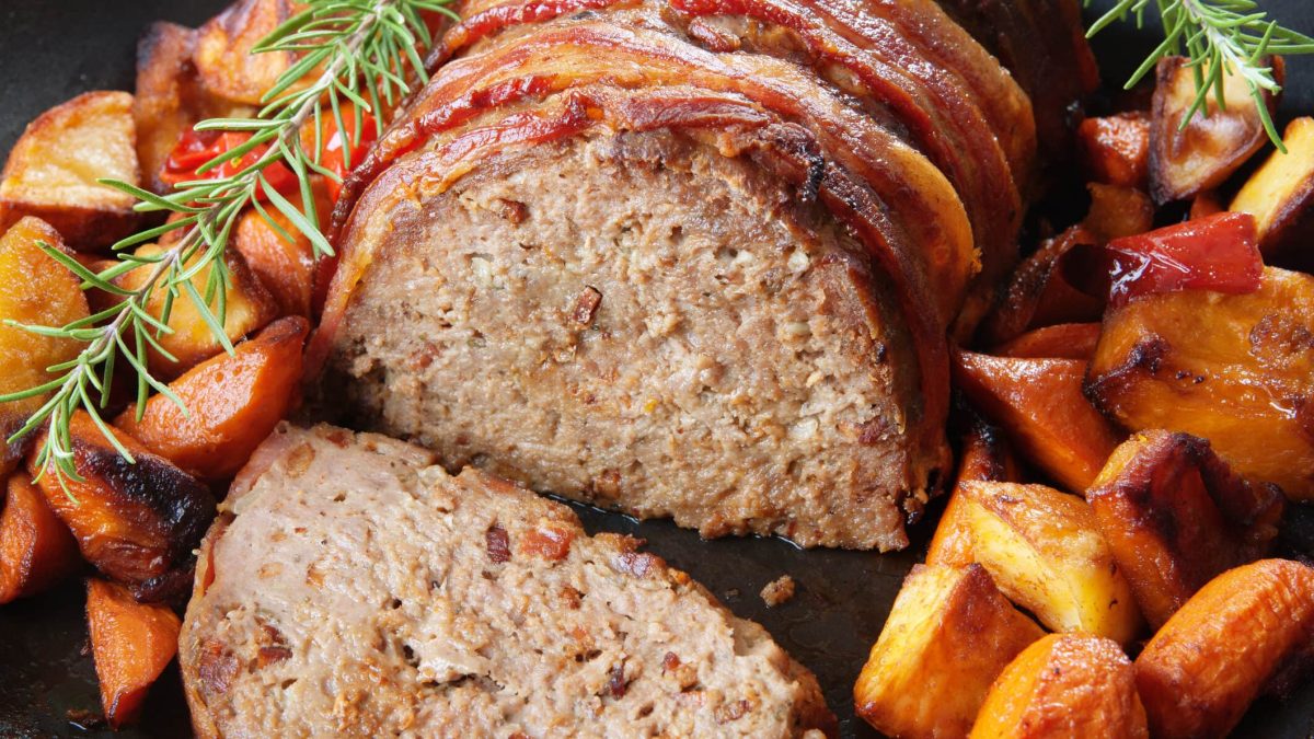 Hackbraten mit gerösteten Kartoffel- und Kürbisspalten angerichtet auf einem Teller.