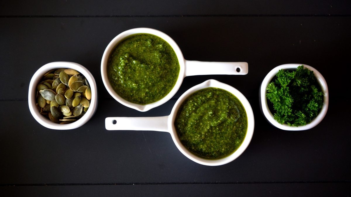 Schalen mit Pesto, Kürbiskernen und frischer Petersilie.