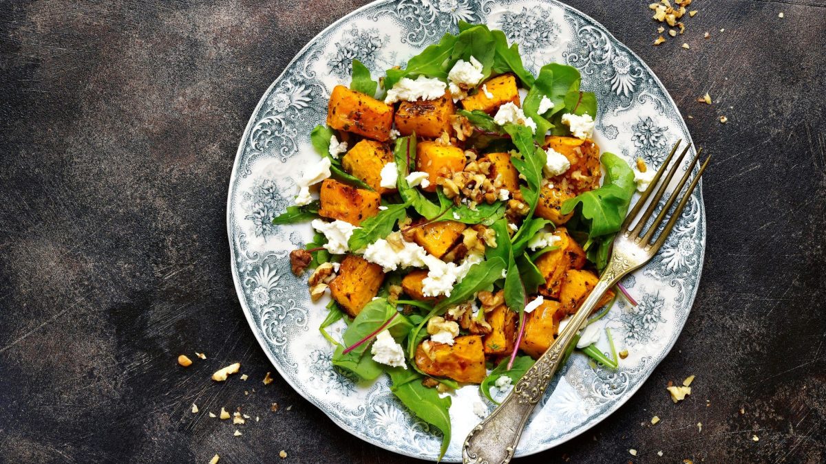 Salat aus Rucola, Kürbis, Feta und Walnuss auf verspieltem Teller