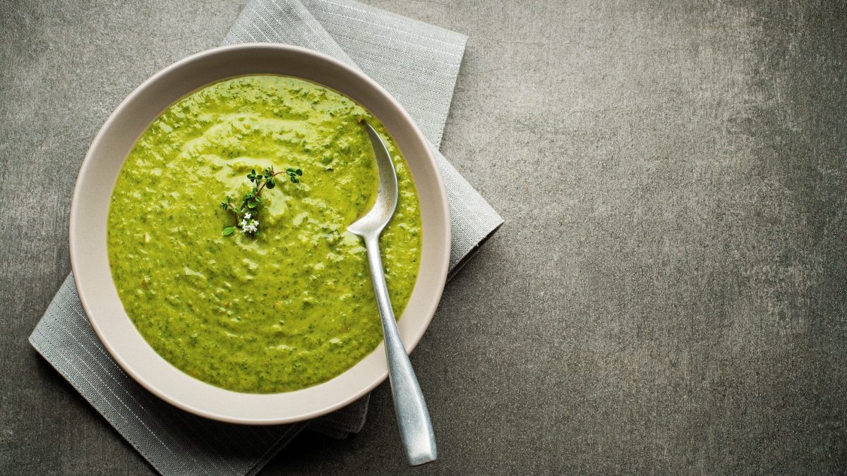 Grüne Suppe auf weißem Teller.