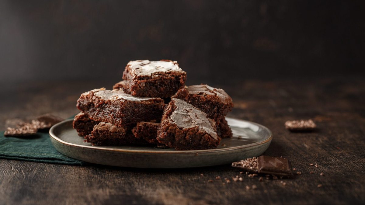 Mehrere Zucchini-Brownies liegen gestapelt auf einem Teller.