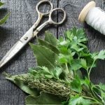 Auf einem Tisch liegt ein gebundenes Sträußchen mit Kräutern. Es handelt sich um ein Bouquet garni.